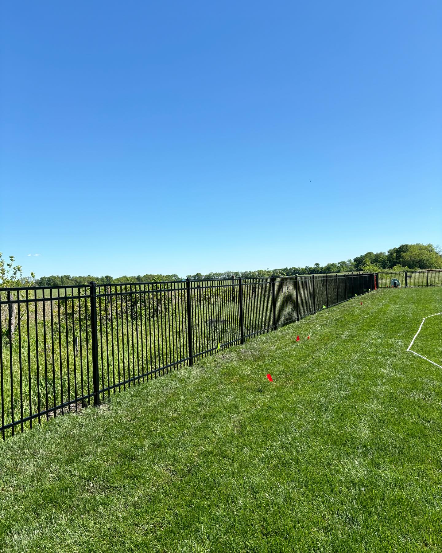 Black aluminum open-view boundary fence on an open lot by RKC Wood Care Pros