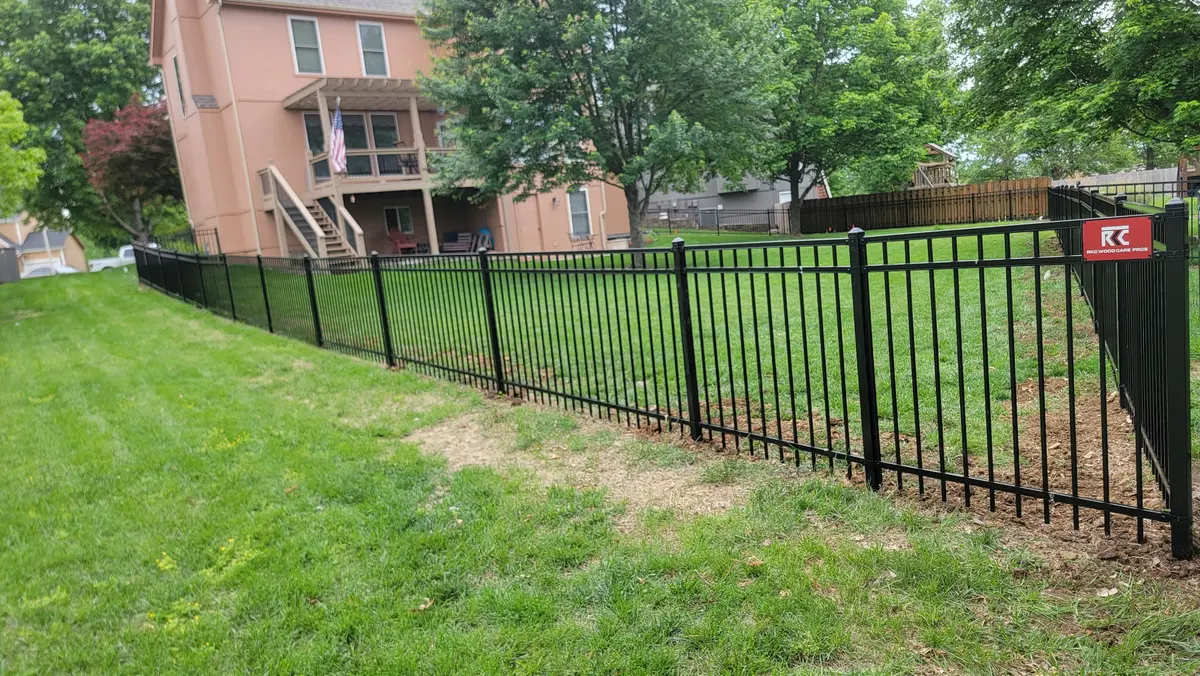 Black ornamental aluminum fence stepped down a sloped backyard by RKC Wood Care Pros