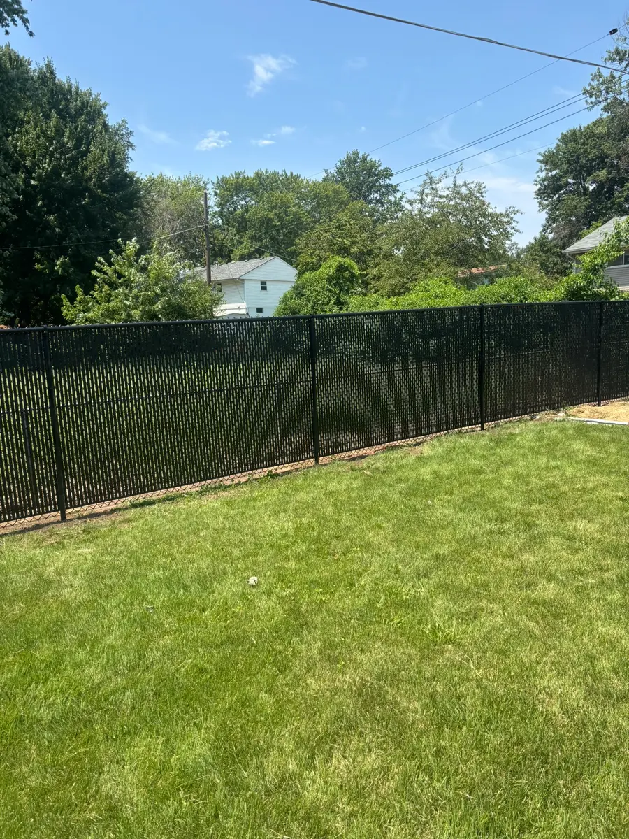 Black vinyl-coated chain link fence securing a residential backyard by RKC Wood Care Pros