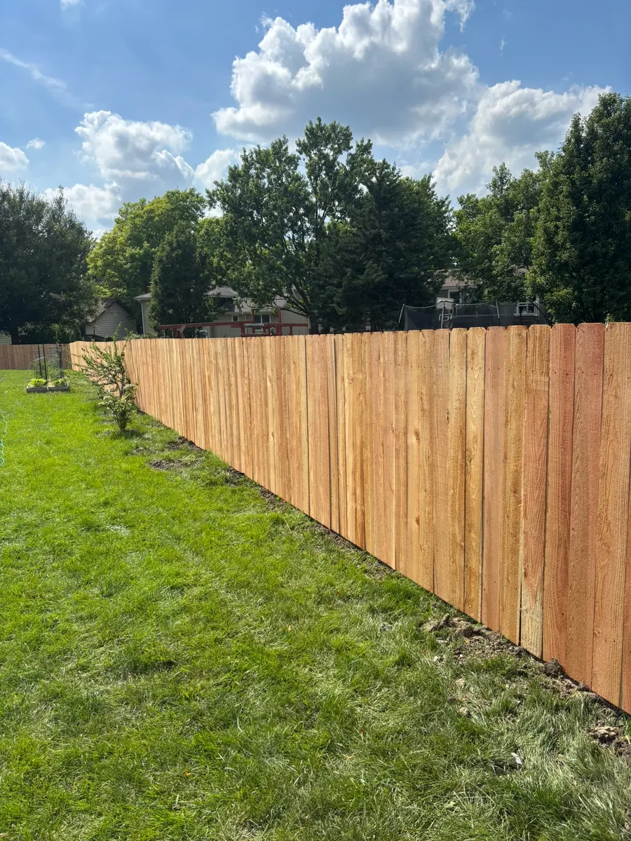 Newly installed cedar dog-ear privacy fence running the length of a backyard by RKC Wood Care Pros
