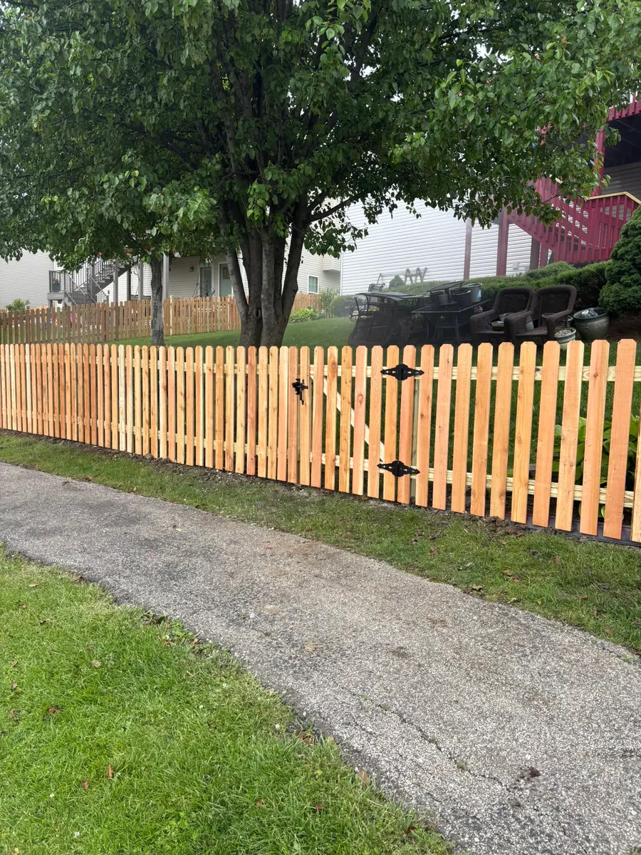 Cedar spaced picket fence with a walk gate along a driveway by RKC Wood Care Pros