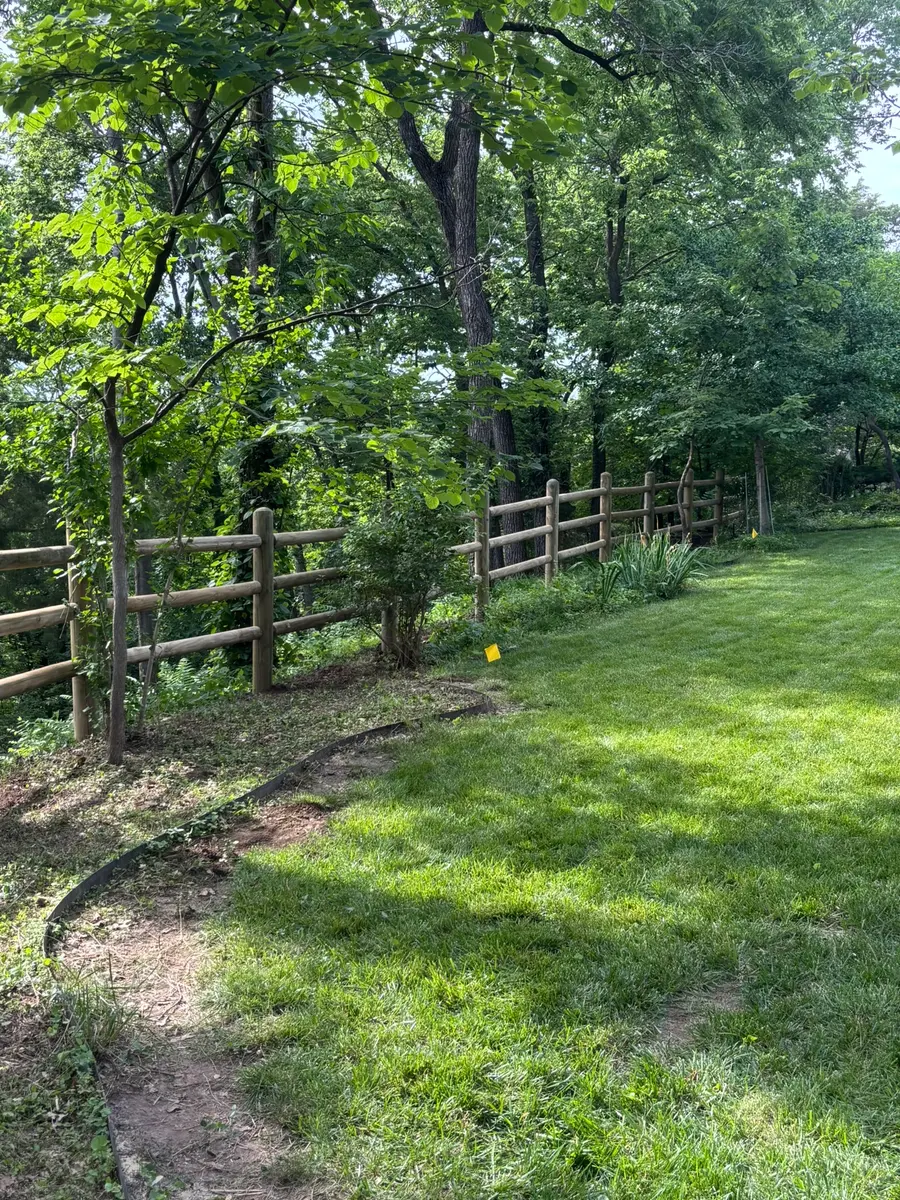 Split rail wood fence marking a wooded property line by RKC Wood Care Pros