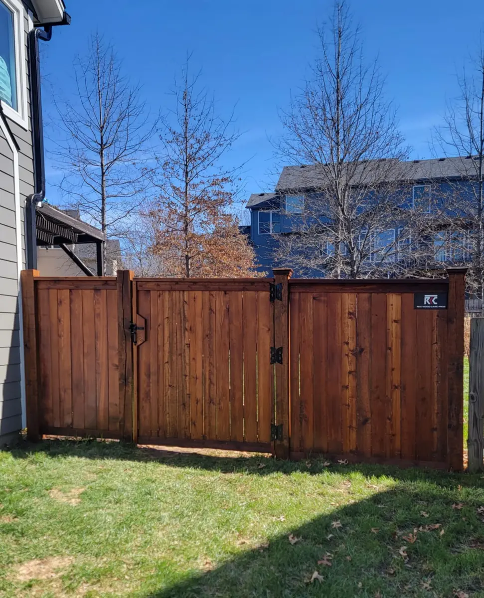 Stained cedar double gate set into a privacy fence between two homes by RKC Wood Care Pros