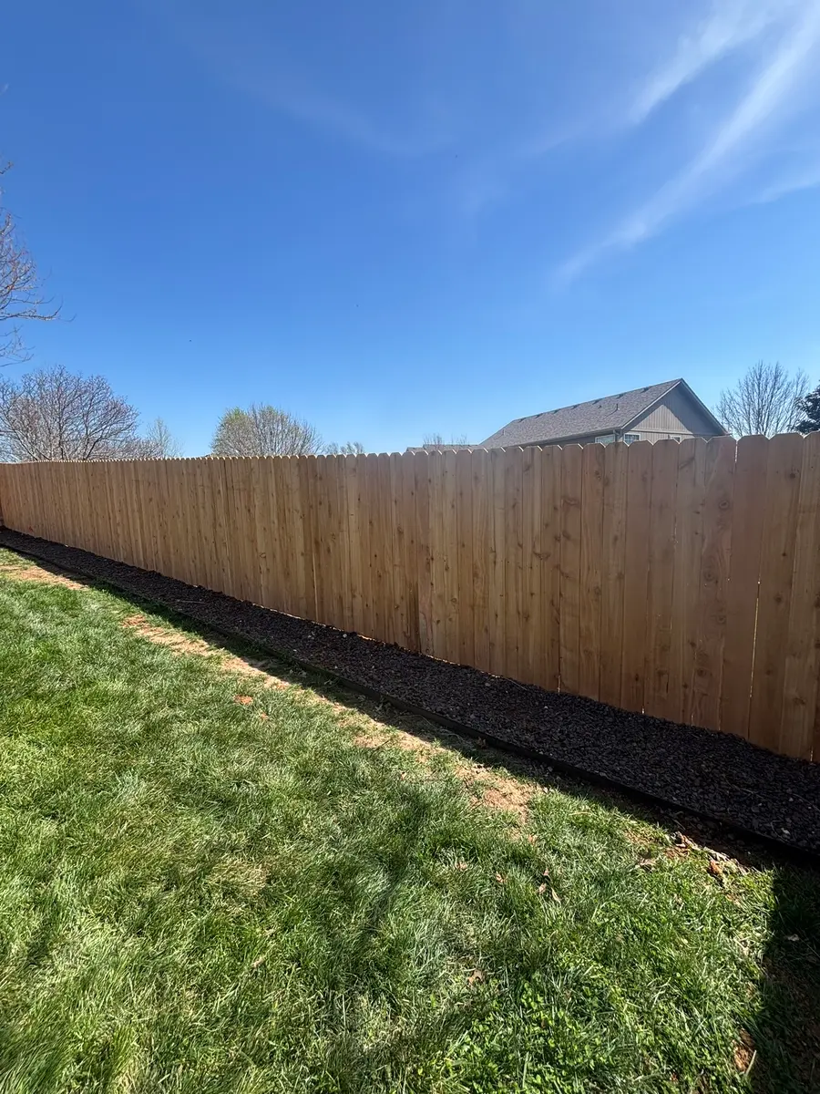 Long run of unstained cedar dog-ear privacy fence along a mulched property line by RKC Wood Care Pros