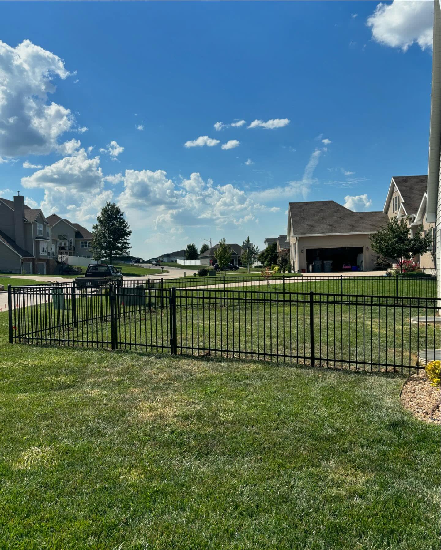 Black ornamental fence with flat-top pickets and walk gate on a front lawn — RKC Wood Care Pros