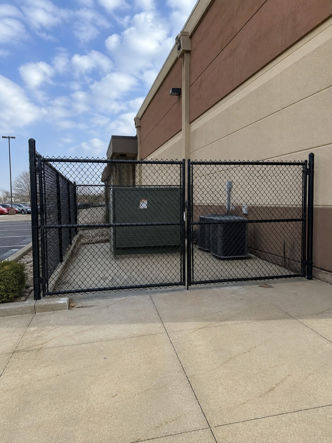 Black chain link utility equipment enclosure at a Kansas City commercial building — RKC Wood Care Pros