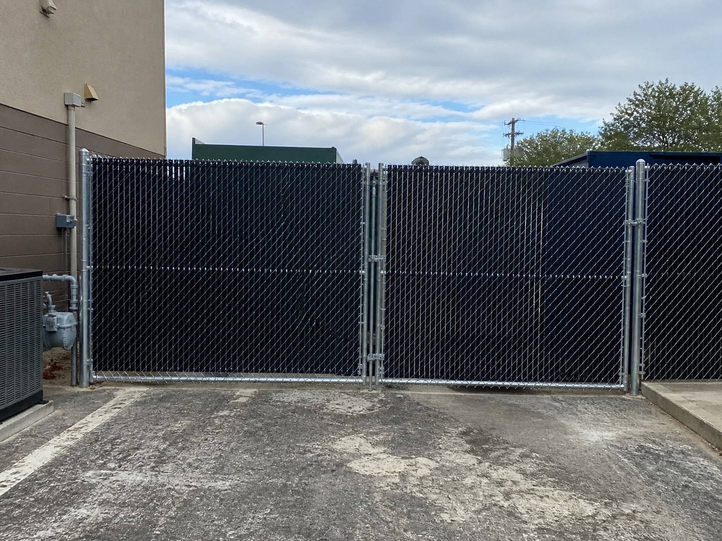 Chain link fence with black privacy slats and double gate at a Kansas City commercial property — RKC Wood Care Pros