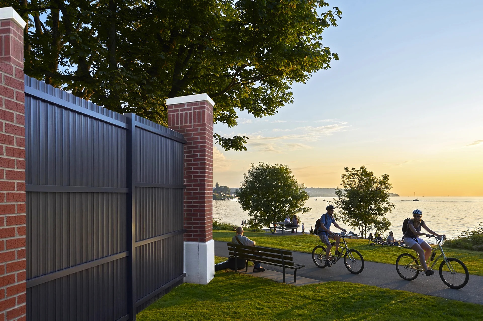 Charcoal composite privacy fence with brick pillars at a waterfront park — RKC Wood Care Pros