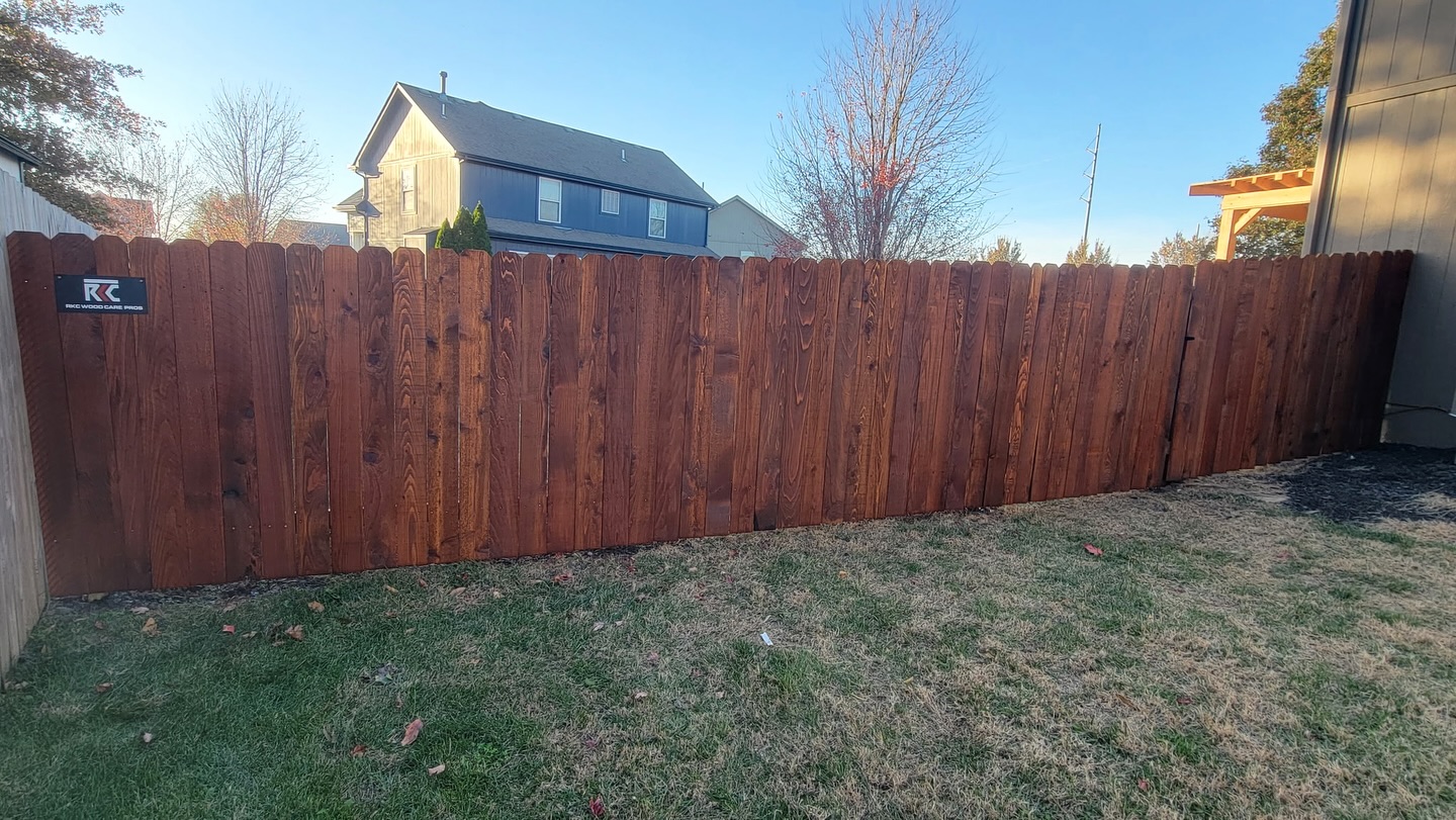 Dark mahogany-stained cedar dog-ear privacy fence with RKC logo tag in Kansas City — RKC Wood Care Pros