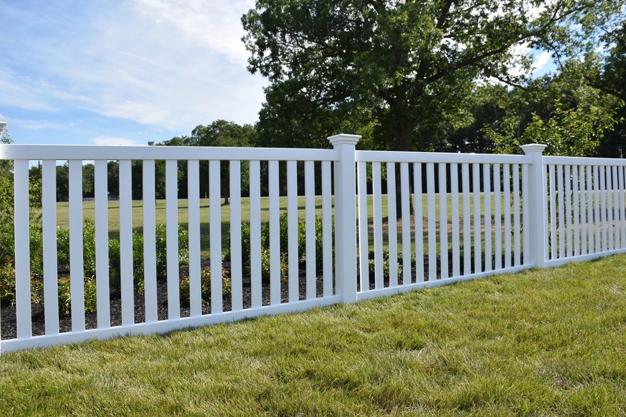 White vinyl spaced picket fence on a green front lawn in the KC metro — RKC Wood Care Pros