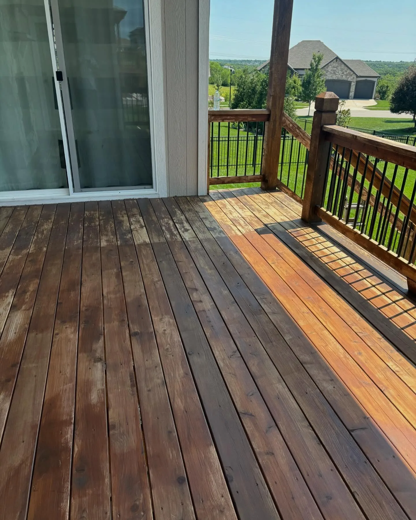 Cedar deck half-stained in Olathe, KS showing sharp contrast between weathered gray left and fresh amber right