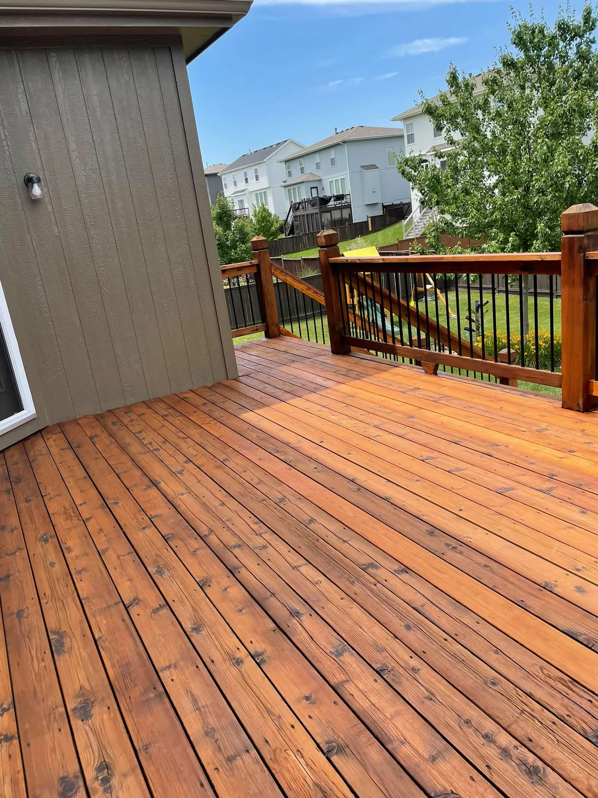 Close view of freshly stained deck boards with black metal railing in Olathe, KS