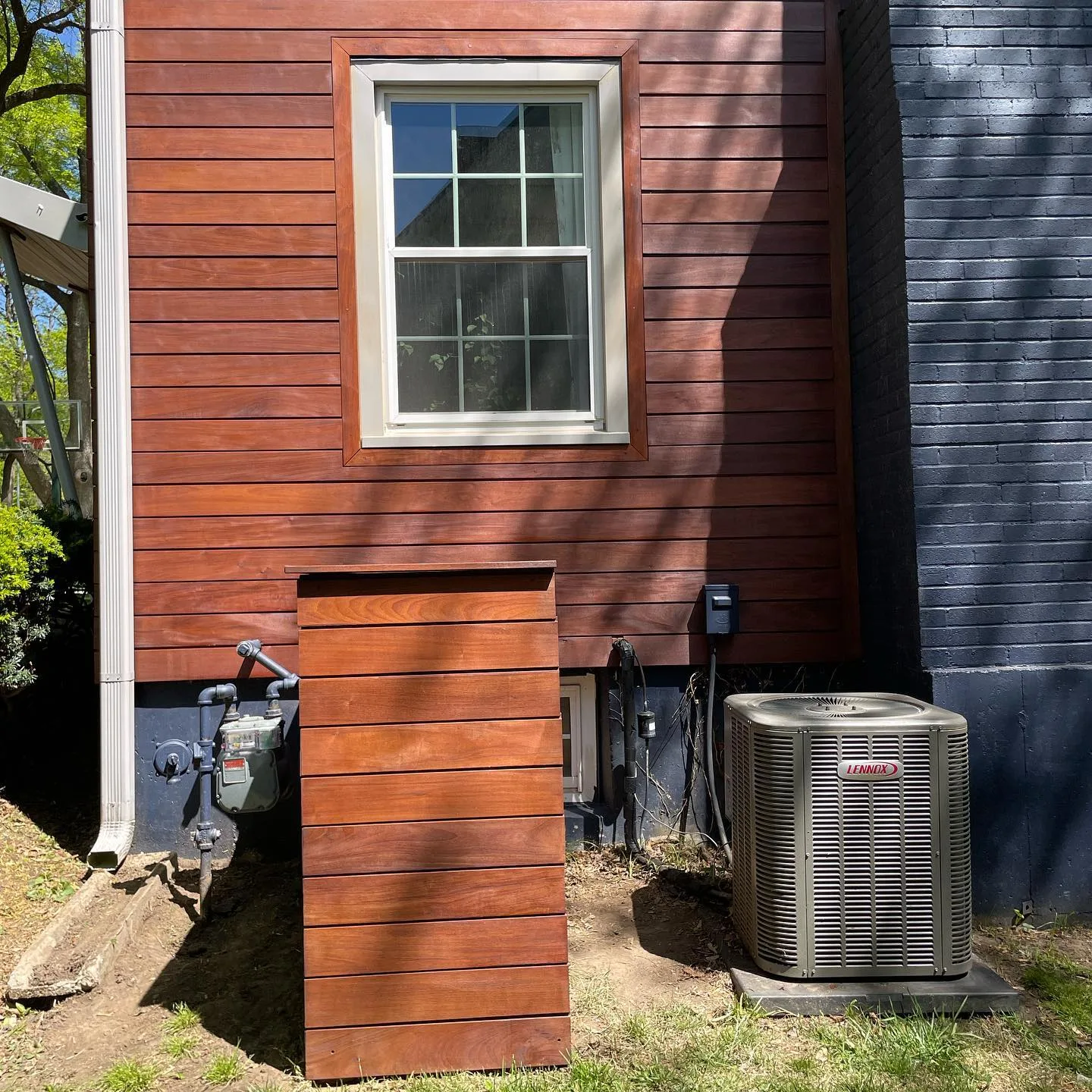 Freshly stained horizontal cedar siding on a Kansas City, MO home — deep red-brown tone, bright window detail