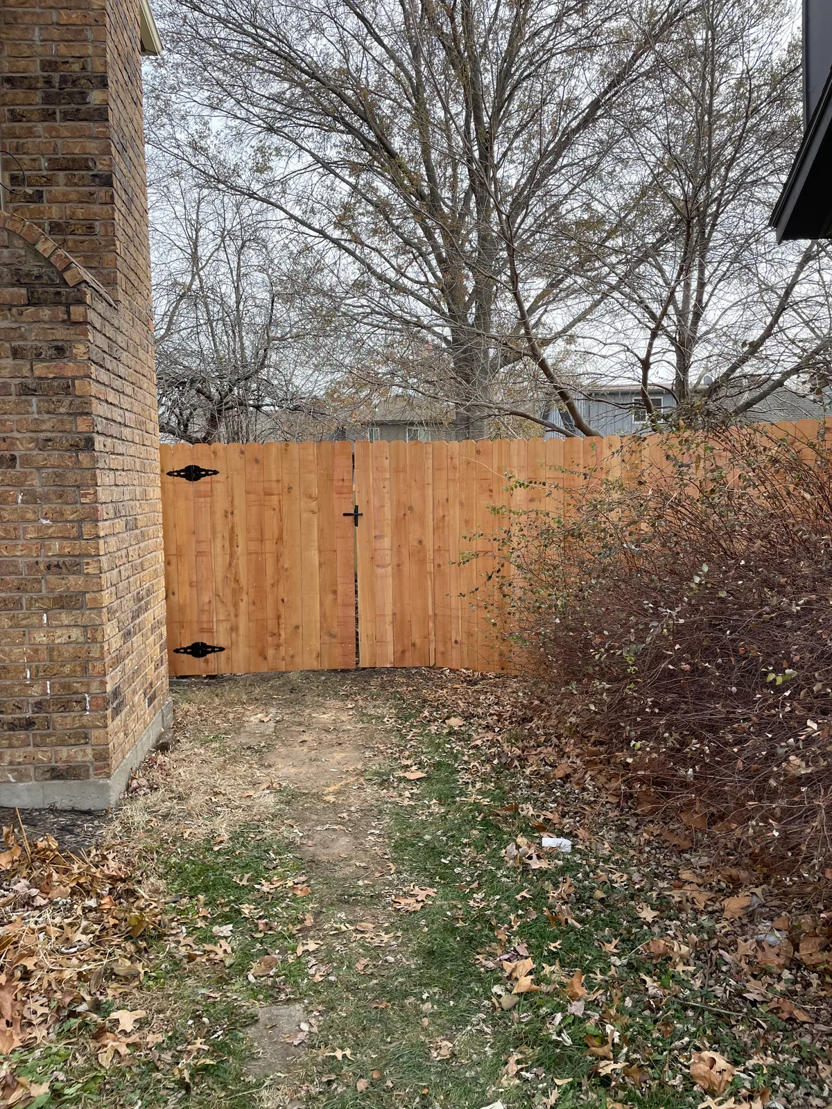 Horizontal cedar fence from second angle in Smithville, MO — winter bare trees in background