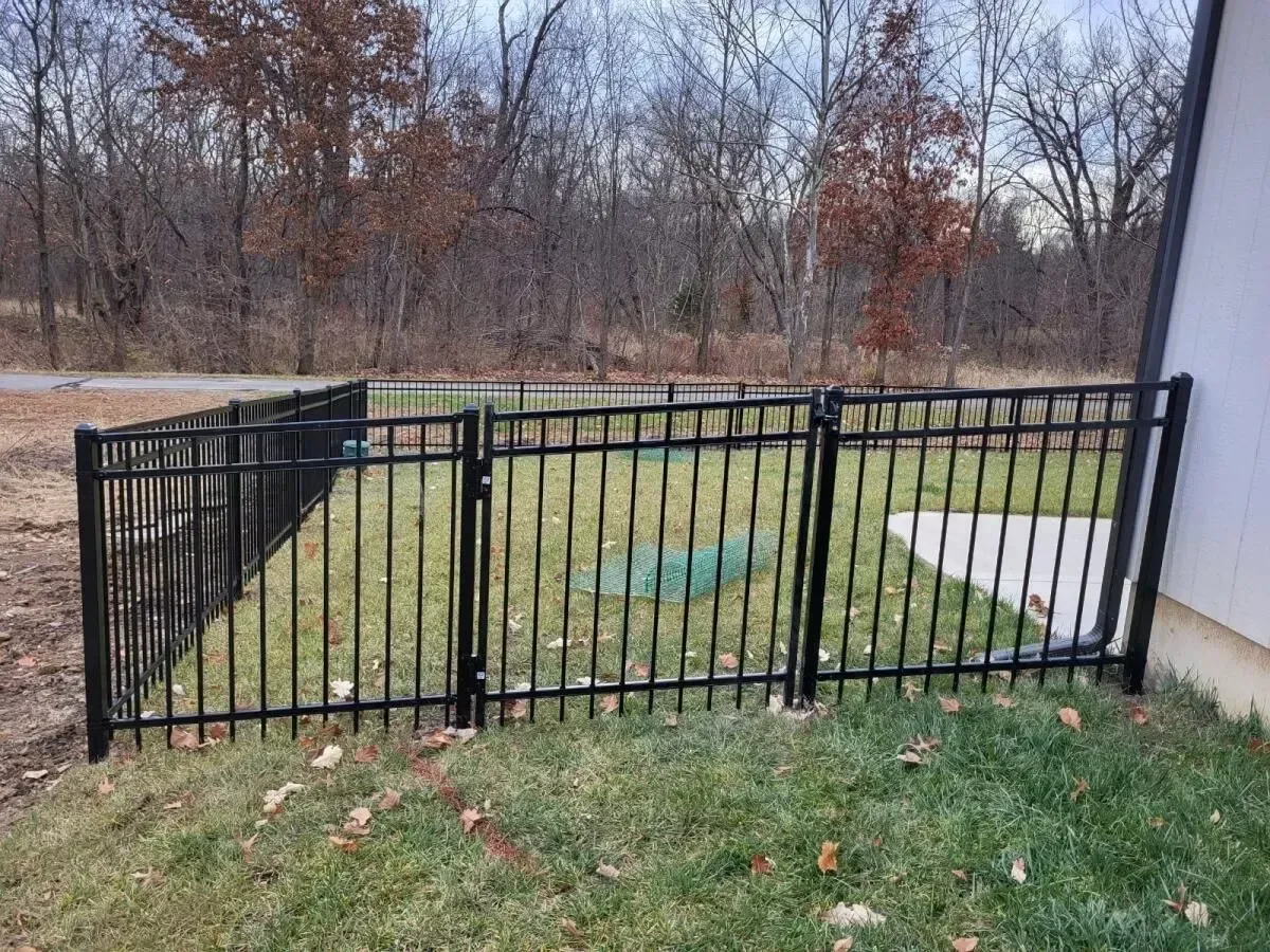 Black ornamental aluminum fence in fall foliage setting in Mission, KS — red and orange maple leaves on ground